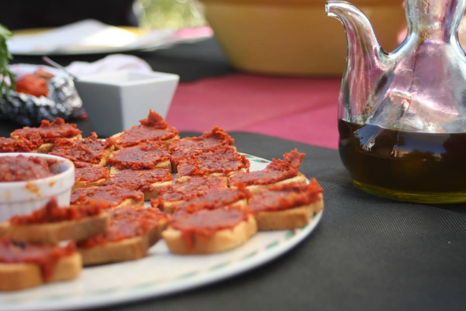 Foto de rebanadas de pan con sobrasada y una bota de vino