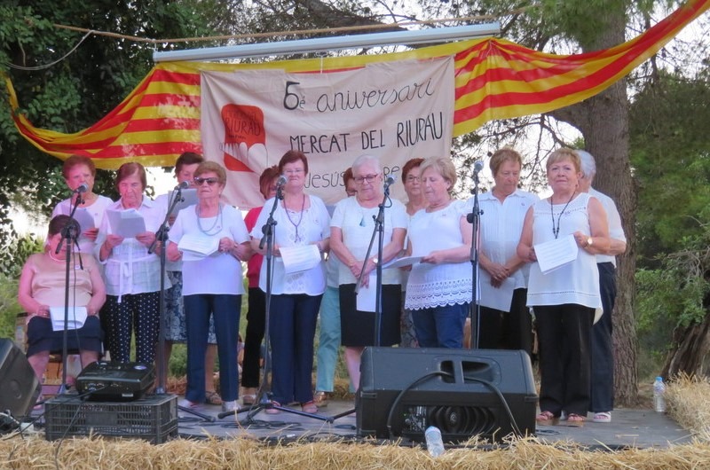 Fotografía del 5º aniversario del Mercat del Riurau de un escenario montado para que cante el coro del pueblo.